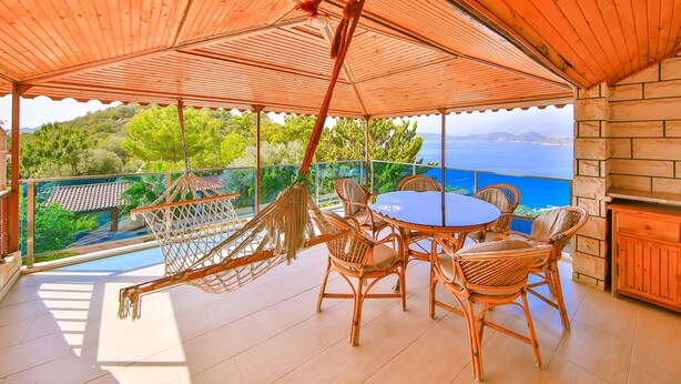 A covered outdoor seating area with wicker furniture and a view of the sea. - Villa Dundar Kas Apartments (Kas)