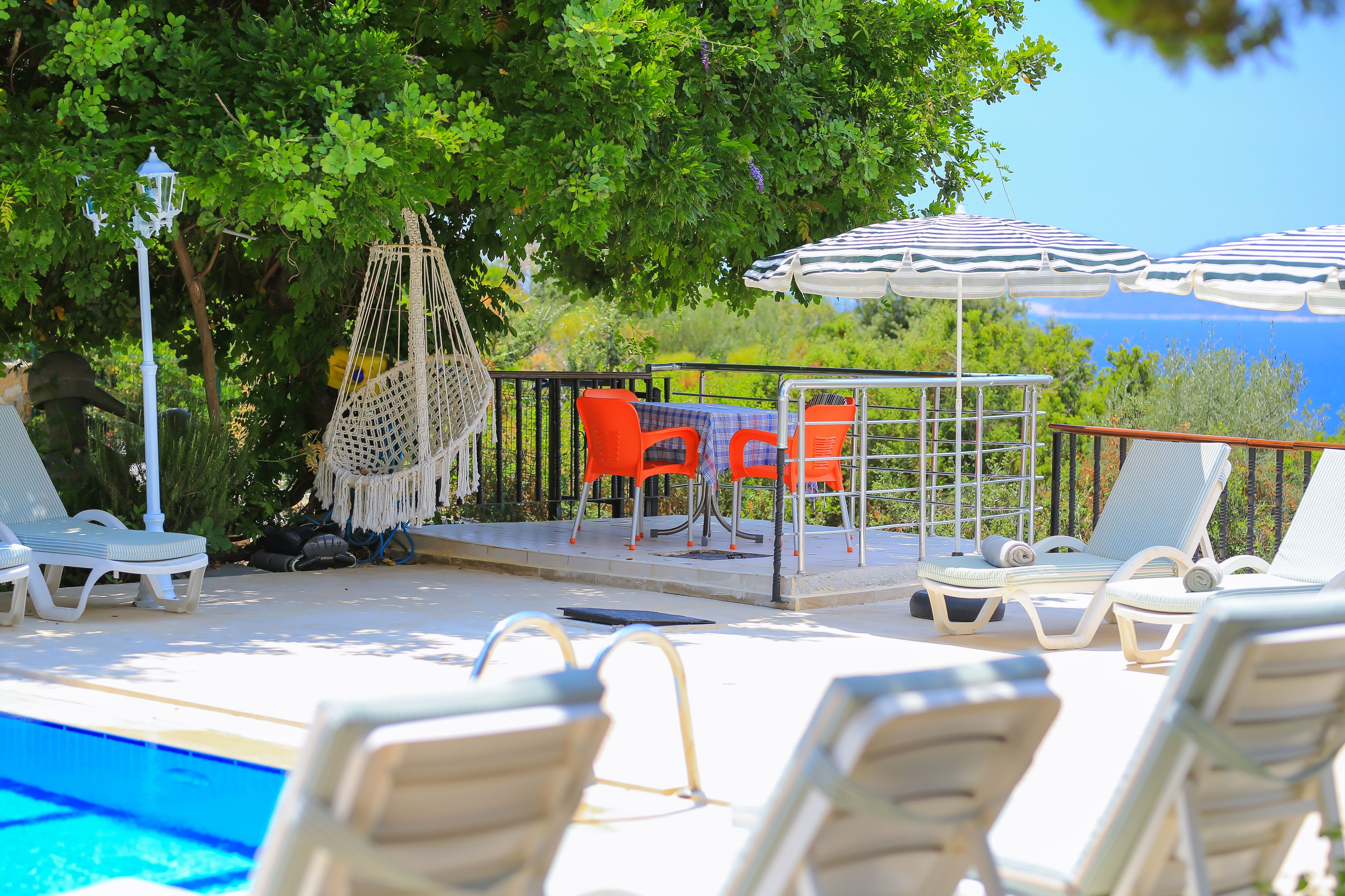 Un espace aménagé au bord de la piscine, avec des chaises longues, une table et des parasols.