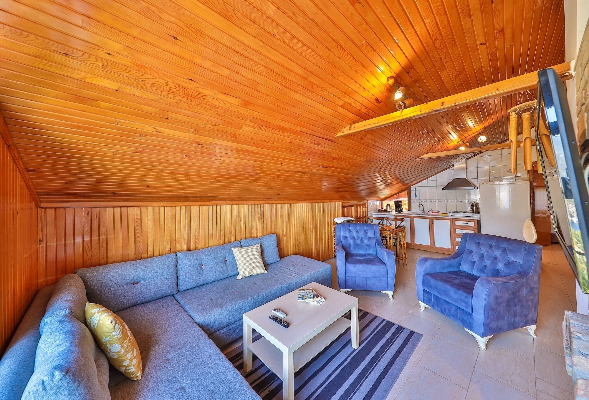 A cozy living area with a wooden ceiling, a sofa, a coffee table, and two armchairs.