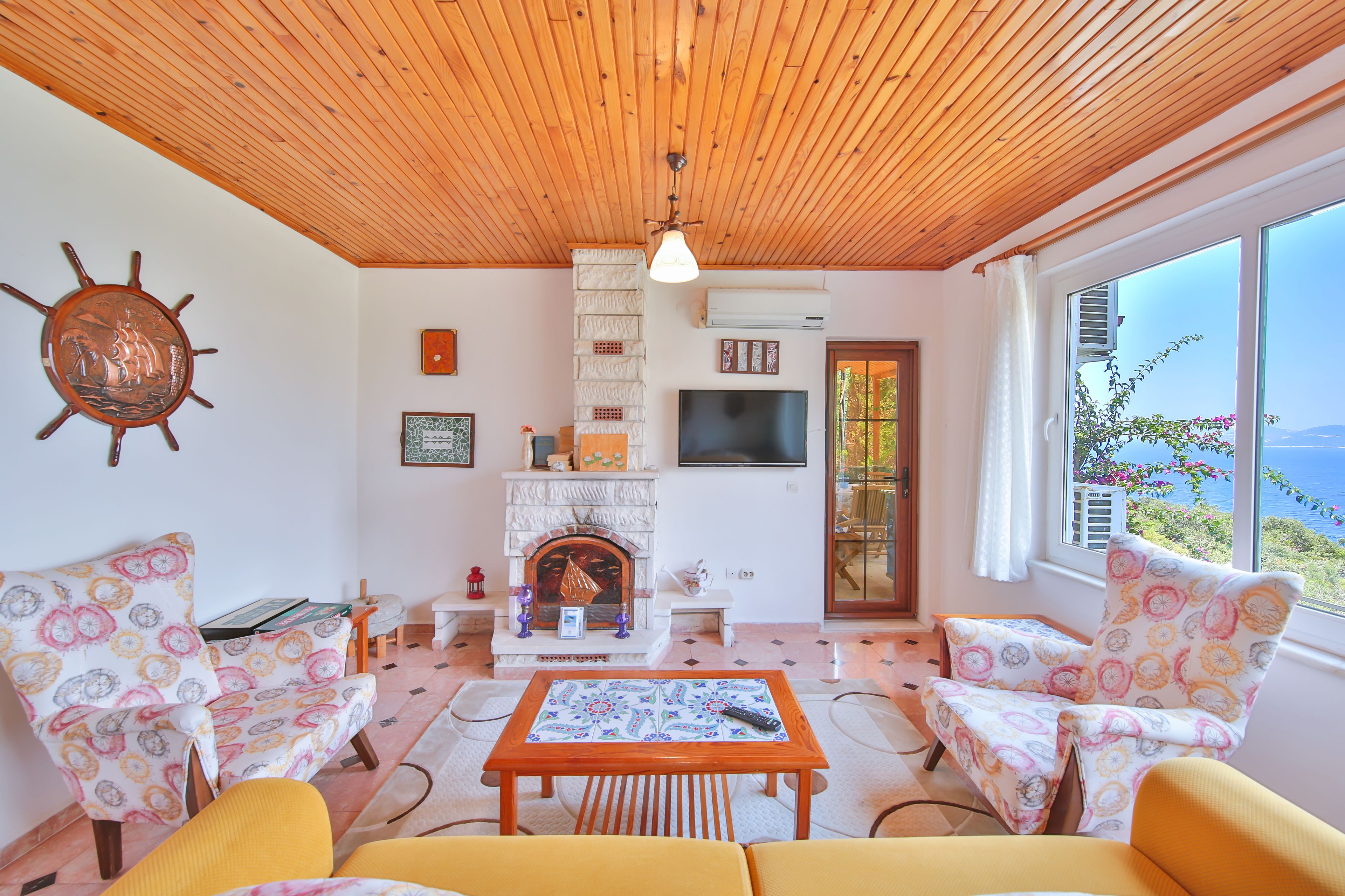 Un accogliente soggiorno con camino, soffitto in legno e ampie finestre con vista panoramica.