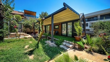 A modern house with a patio, a garden, and a view of neighboring buildings.