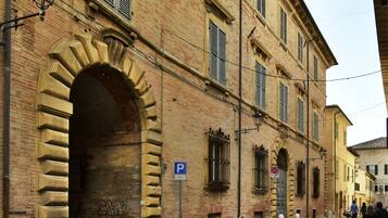 A historic building with a large arched entrance, a cobblestone street, and a blue parking sign.