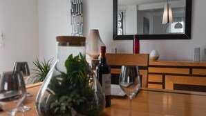 Een eettafel met wijnglazen, een wijnfles en een decoratieve vaas met planten.