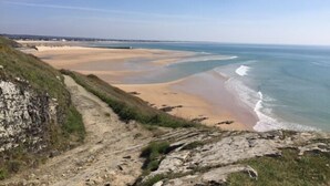 Een kustlandschap met een zandstrand, rotsachtige kliffen en een heldere lucht.