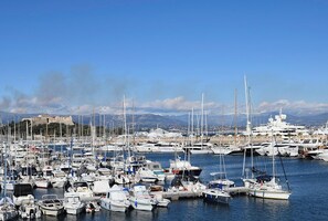 A marina with numerous boats docked, a clear sky, and a mountainous backdrop.