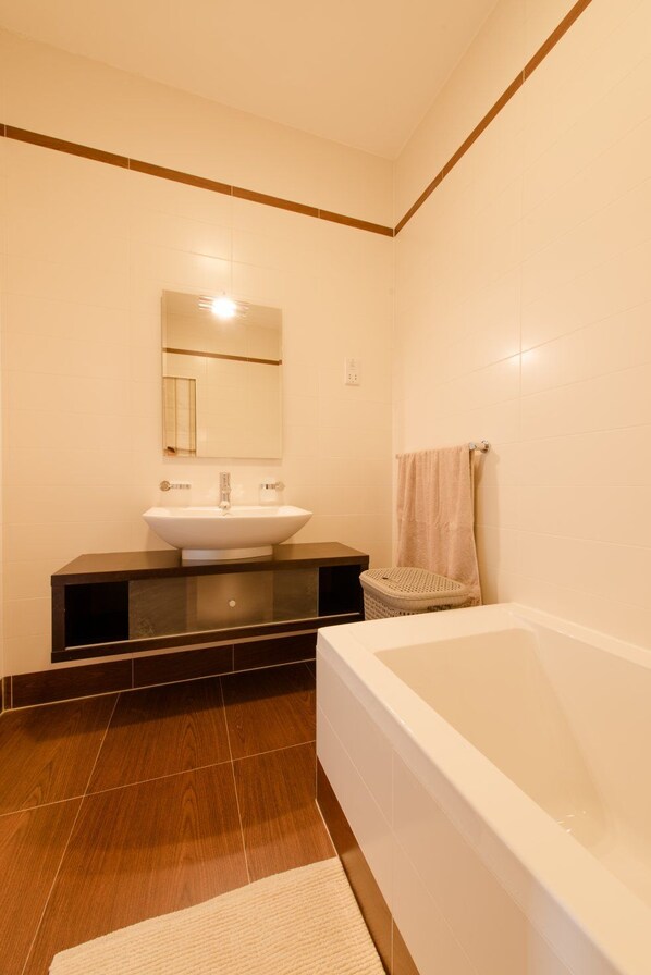 Een moderne badkamer met een groot bad, een wastafel en een spiegel.