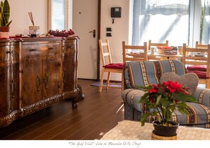 Una sala de estar con un aparador de madera, un sofá con cojines estampados y una planta en maceta.