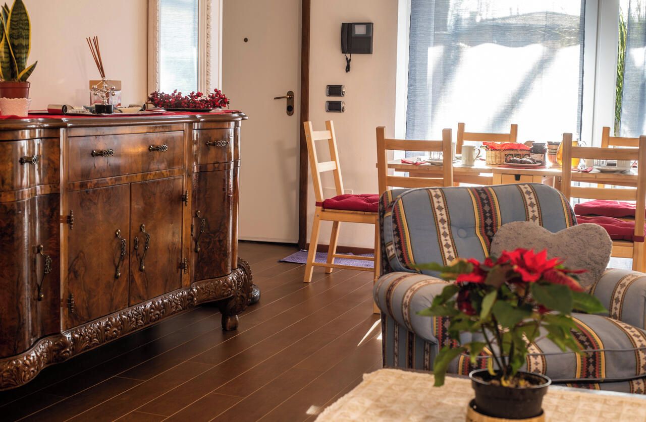Ein Wohnzimmer mit einem Holzkabinett, einer Couch und einem Esstisch mit Stühlen.
