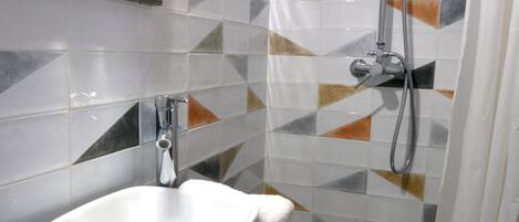A bathroom with a white sink, a shower with a handheld showerhead, and a tiled floor with geometric patterns.