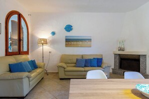 A living room with two sofas, a table, a fireplace, a lamp, and wall art.