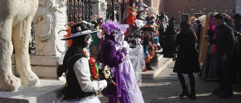 A historical square with statues, a clock tower, and people in period costumes.