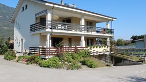Un edificio a due piani con un balcone, un piccolo giardino e un vialetto lastricato.