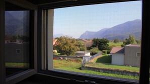 Una finestra con vista su una zona residenziale, tra cui case e una montagna sullo sfondo.