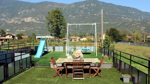 Un patio con tavolo, sedie, uno scivolo e un'altalena.