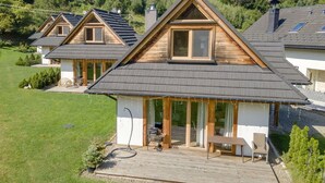 Ein modernes Haus mit geneigtem Dach, großen Fenstern und einer Terrasse.