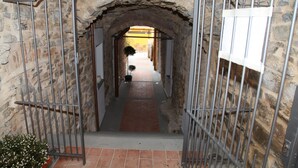 Un arc en pierre mène à un couloir bordé de rambardes métalliques de chaque côté.