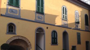 Un bâtiment jaune doté de nombreuses fenêtres en arc et d’un arc en pierre à l’entrée.