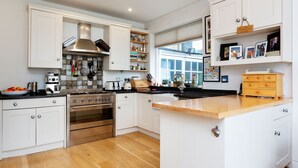 Una cucina moderna con mobili bianchi, elettrodomestici in acciaio inossidabile e un piano di lavoro in legno.