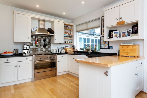 Una cocina moderna con muebles blancos, electrodomésticos de acero inoxidable y encimera de madera.