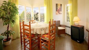 Un coin repas avec une table ronde, des chaises en bois, une lampe et une plante en pot.