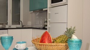 Una cocina moderna con armarios color turquesa, un refrigerador blanco y una cesta de frutas en la encimera.