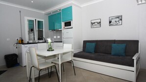 Un espacio habitable compacto con kitchenette, comedor y sofá.