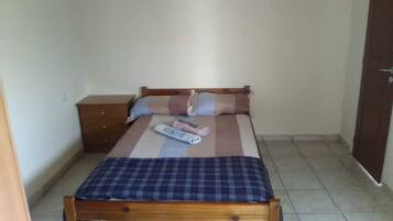 Un dormitorio pequeño y sencillo con una cama de madera, una mesita de noche y una pared sin decorar.