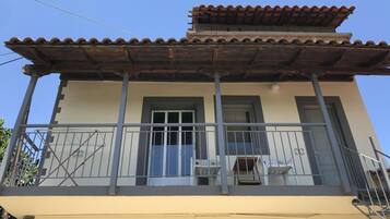 Un immeuble de deux étages doté d’un balcon, d’un toit en tuiles et d’une façade beige.