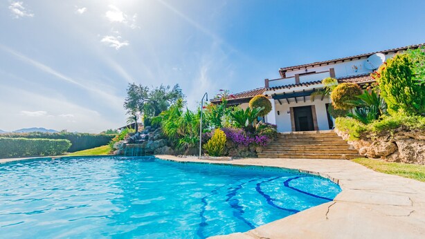 Vista a la piscina de una casa, con cielo azul despejado, piscina y escalera que lleva a la entrada.