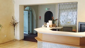 A reception area with a counter, a potted plant, and a door leading to another room. - Albero (Swinoujscie)