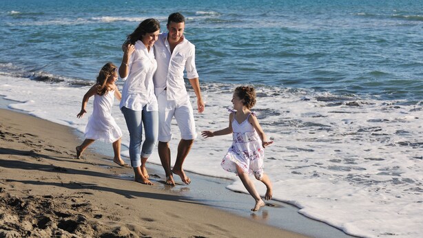 A family walking along a sandy beach with the ocean in the background. - Albero (Swinoujscie)