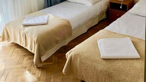 A hotel room with two beds, a wooden floor, a window with sheer curtains, and a bedside table with a lamp. - Albero (Swinoujscie)