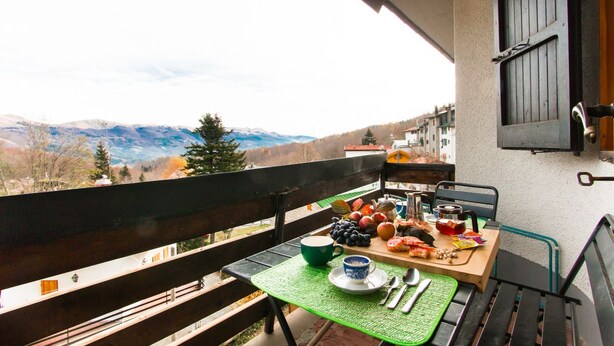 Ein Balkon mit Frühstückstisch, mit Blick auf eine Berglandschaft.