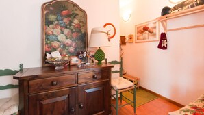 Ein hölzerner Kommode mit Schubladen, eine wandmontierte Uhr, ein gerahmtes Blumenbild und ein kleiner Tisch mit Lampe und Dekoration.