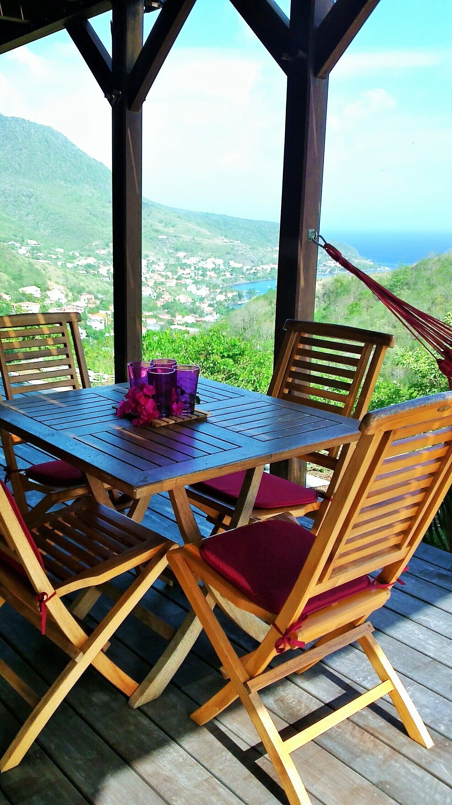 An outdoor wooden deck with a table and chairs, overlooking a mountainous landscape.