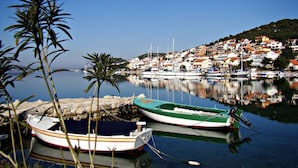 Un puerto con barcos amarrados, agua tranquila y una colina con edificios al fondo.