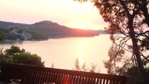 Una mesa de madera con vistas a un lago al atardecer.