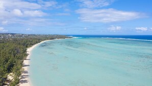 Vista aérea de uma praia com águas turquesa cristalinas e área arborizada.