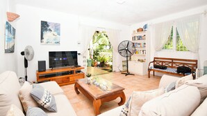 Uma sala de estar com televisão, sofá, mesa de centro e estante de livros.