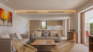 A modern living room with a sofa, two wicker chairs, a coffee table, and a kitchen in the background. - Can Ribas - Spectacular villa with pool near Palma (Marratxi)