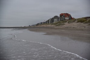 Una playa con una hilera de edificios de varios pisos, incluyendo una estructura destacada de techo rojo.