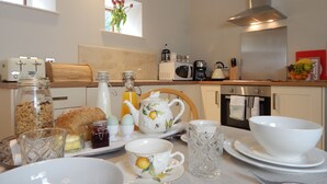 Une table dressée pour le petit-déjeuner, avec un grille-pain, une bouilloire et divers aliments pour le petit-déjeuner.