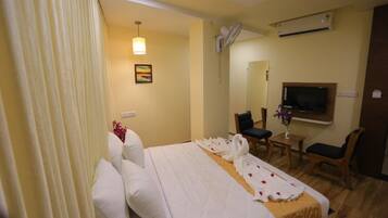 Una habitación de hotel con cama, escritorio, silla, televisión y espejo.