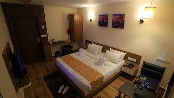 Una habitación de hotel con cama, mesita de noche, silla y escritorio con lámpara.
