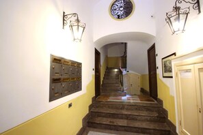 A staircase with a metal railing, a wall-mounted light fixture, and a door with a sign.