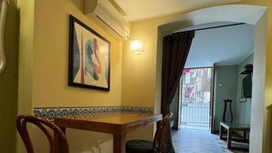 A dining area with a wooden table and chairs, a framed artwork on the wall, and a tiled floor. - Convenient and cozy apartment in the heart of the city nearby historic center (Palermo)