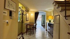 A hallway with a staircase, a dining area with chairs and a table, and a refrigerator. - Convenient and cozy apartment in the heart of the city nearby historic center (Palermo)