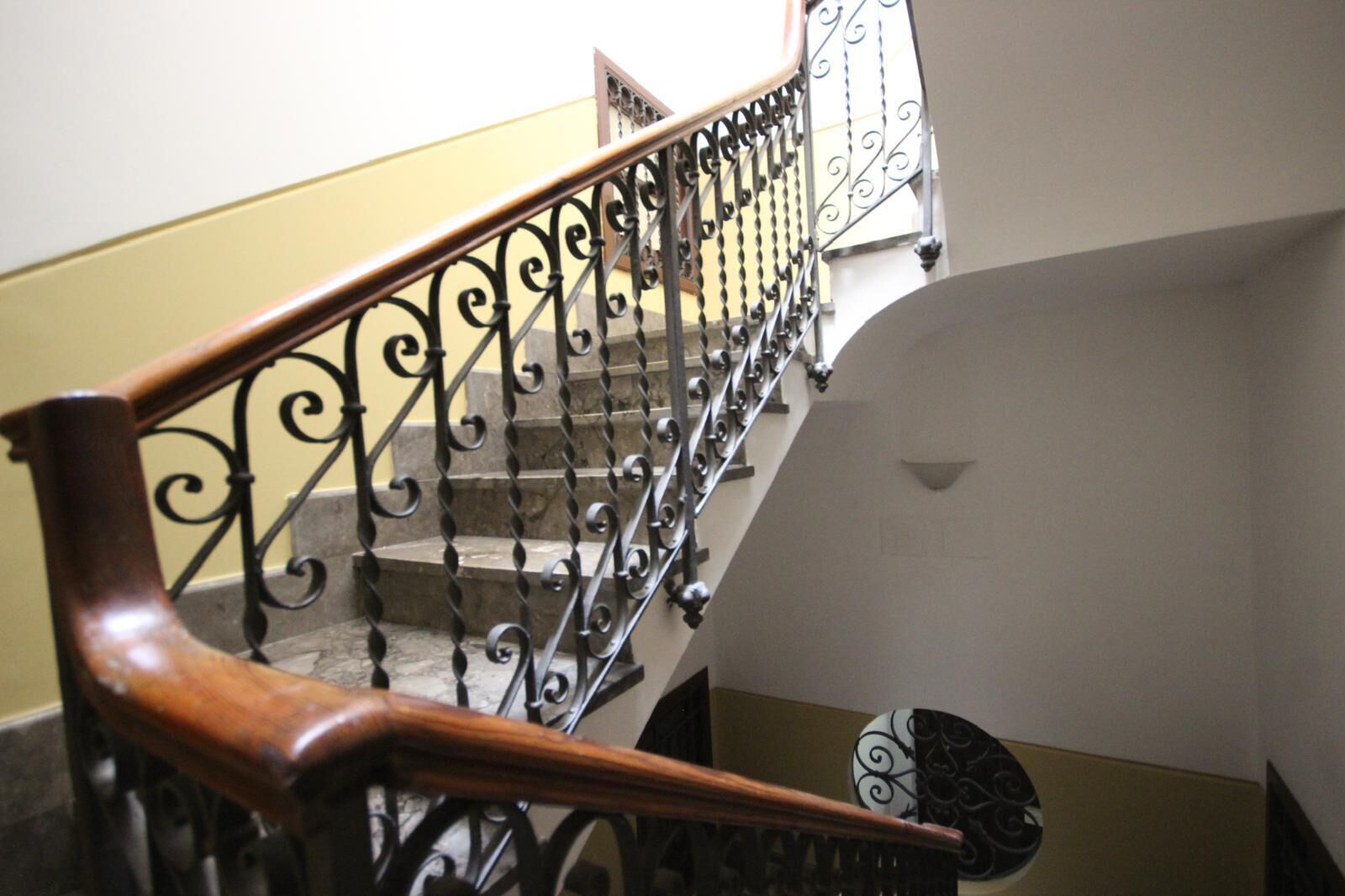 A staircase with ornate black metal railings and wooden handrails.