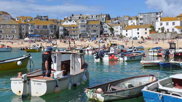 Un pueblo costero con playa, barcos e históricos edificios.