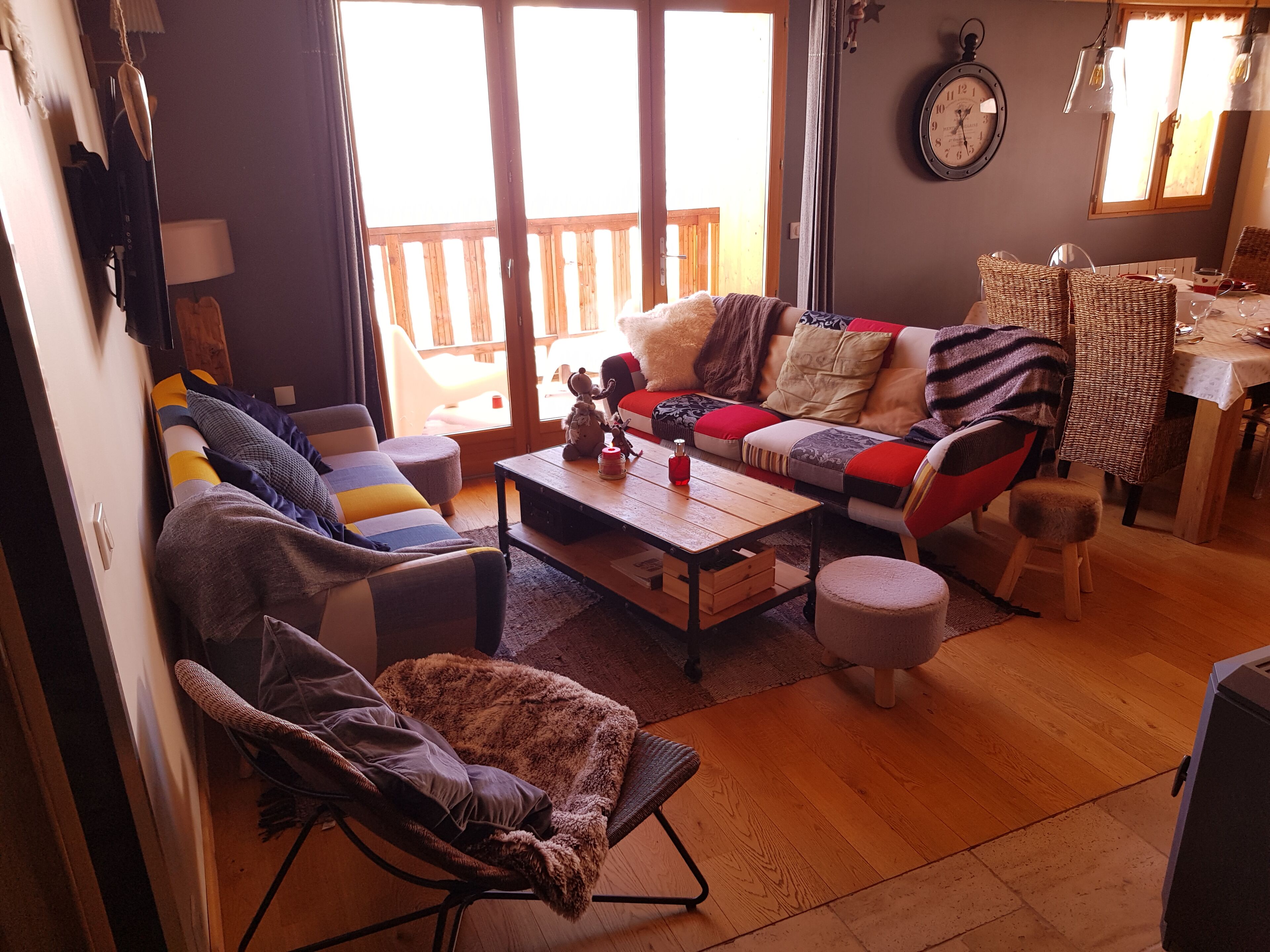 A cozy living room with a sofa, armchair, and a dining table with chairs.